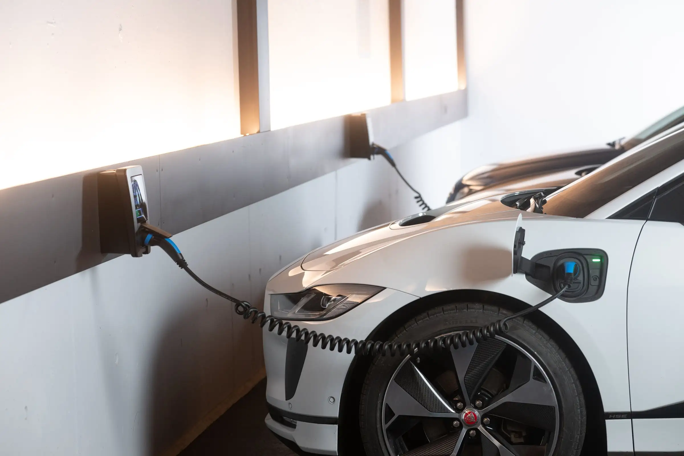 White electric car charging from a wall charger in a garage